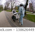 Woman walking with baby stroller in urban park 138626449