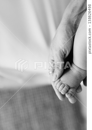 Close View Of Adult Hand Holding Fragile Newborn Toes Peacefully Close View Of Adult Hand Holding Fragile Newborn Toes Peacefully 138626498