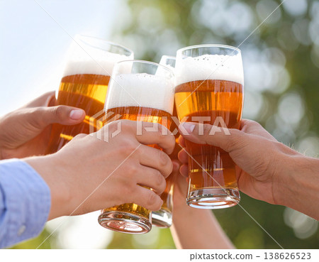特寫：雙手舉杯，碰杯暢飲冰啤酒，啤酒表面泛著誘人的泡沫。 138626523