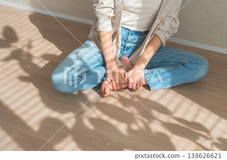 夕陽西下，一位身穿牛仔服的女子坐在木地板上。 138626621