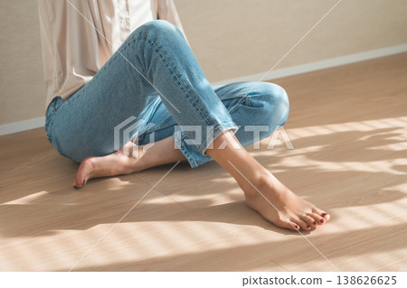 夕陽西下，一位身穿牛仔服的女子坐在木地板上。 138626625