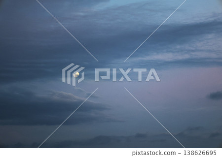 傍晚的月亮在雲層間緩緩移動。 138626695