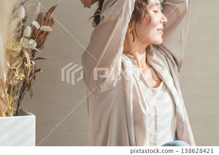 一位神態放鬆的女士在客廳裡沐浴在陽光下。 138628421