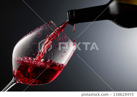 Red wine is poured from a bottle into a glass. Red wine is poured from a bottle into a glass. 138628455