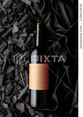 Bottle of red wine against a backdrop of charcoal and black satin. Bottle of red wine against a backdrop of charcoal and black satin. 138628456