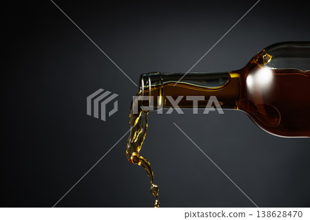 White wine of a rich amber color pours out of the bottle. 138628470