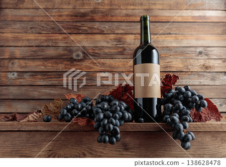 Red wine bottle with blue grapes on an old wooden table. Red wine bottle with blue grapes on an old wooden table. 138628478