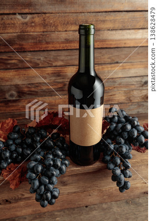 Red wine bottle with blue grapes on an old wooden table. Red wine bottle with blue grapes on an old wooden table. 138628479