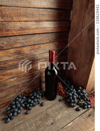 Red wine bottle with blue grapes on an old wooden table. Red wine bottle with blue grapes on an old wooden table. 138628481