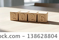 Wooden blocks spelling out the year 2026 on a light wooden table bathed in natural sunlight 138628804