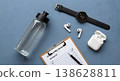 Workout checklist with water bottle watch and headphones on blue background fitness and healthy lifestyle concept 138628811