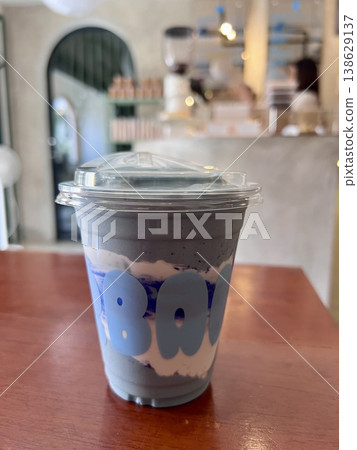 Healthy blue spirulina yoghurt smoothie shake in plastic takeaway cup on wooden table in cafe 138629137