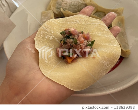 Raw Pork And Vegetable Dumpling Filling On Wrapper Held Over Plate 138629398