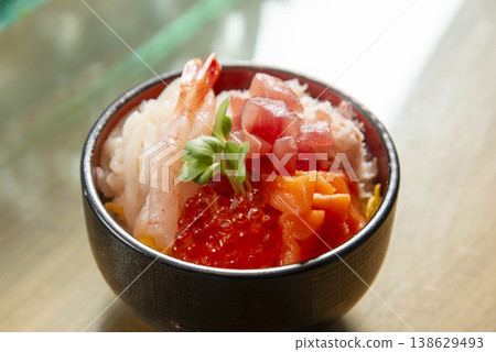 A luxurious Japanese seafood rice bowl featuring sweet shrimp, salmon roe, tuna, and salmon, served in a black bowl. A luxurious Japanese seafood rice bowl featuring sweet shrimp, salmon roe, tuna, and salmon, served in a black bowl. 138629493
