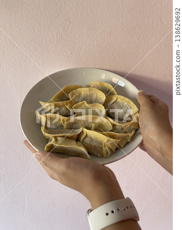Close Up Of Hands Holding Plate Of Raw Folded Pork And Vegetable Dumplings Close Up Of Hands Holding Plate Of Raw Folded Pork And Vegetable Dumplings 138629692