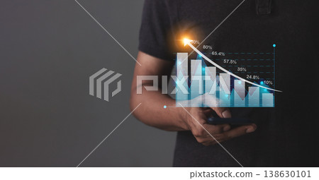Young man with smartphone hand touching to visualize money growth The phone screen displays graphs and charts showing increasing investment and savings trends, along with an increased account balance Young man with smartphone hand touching to visualize money growth The phone screen displays graphs and charts showing increasing investment and savings trends, along with an increased account balance 138630101