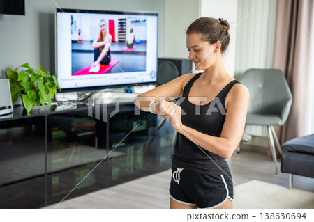 Young woman looking at fitness tracker displaying heart rate, steps count and burnt calories. Smart watch on female hand, point of view, concept of staying fit at home. Young woman looking at fitness tracker displaying heart rate, steps count and burnt calories. Smart watch on female hand, point of view, concept of staying fit at home. 138630694