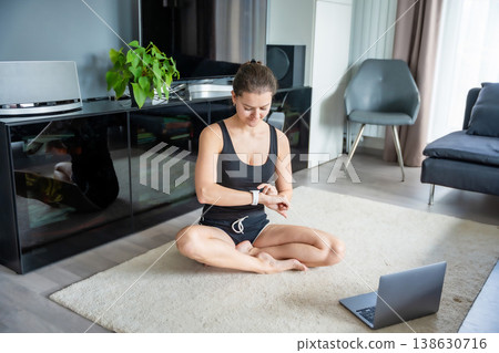 Young woman looking at fitness tracker displaying heart rate, steps count and burnt calories. Smart watch on female hand, point of view, concept of staying fit at home. Young woman looking at fitness tracker displaying heart rate, steps count and burnt calories. Smart watch on female hand, point of view, concept of staying fit at home. 138630716