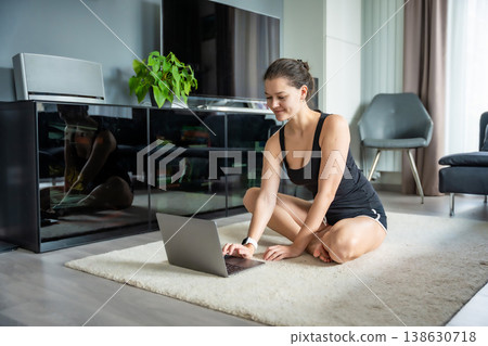 Young woman in sportswear preparing to fitness exercises on mat in living room. Online workout, practicing and meditation at home.  138630718