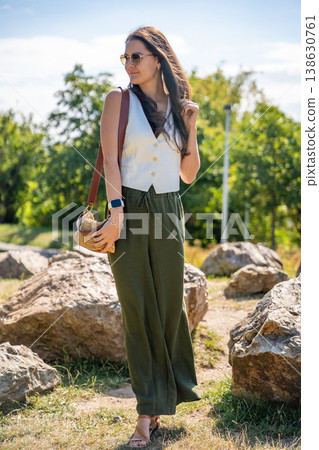 Young woman dressed in white vest and green trousers posing outdoors in Old Money style. Concept of timeless elegance, fashion confidence and classic aesthetic in modern lifestyle. Young woman dressed in white vest and green trousers posing outdoors in Old Money style. Concept of timeless elegance, fashion confidence and classic aesthetic in modern lifestyle. 138630761