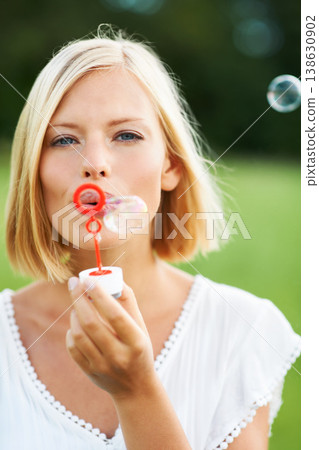 Woman, portrait and blowing bubbles in nature for fun day or playing at outdoor park. Face of young happy female person or blonde with stick or wand to blow bubble on playful holiday or summer break Woman, portrait and blowing bubbles in nature for fun day or playing at outdoor park. Face of young happy female person or blonde with stick or wand to blow bubble on playful holiday or summer break 138630902