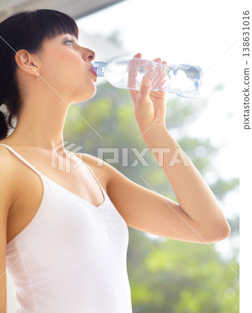 Drinking water, fitness and woman with health, exercise and lens flare with hydration, wellness and sports. Person, happy girl or athlete with liquid, aqua and workout with training, thirsty or relax 138631016
