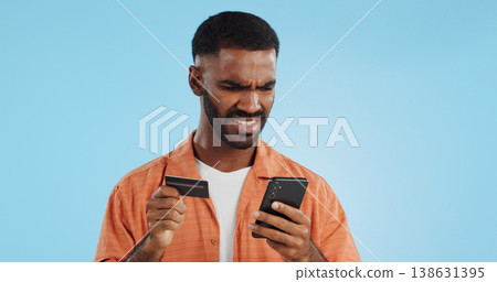 Man, credit card and confused with phone, studio and thinking of price, code or info by blue background. Online shopping, payment glitch or mistake with declined account with fintech with smartphone 138631395