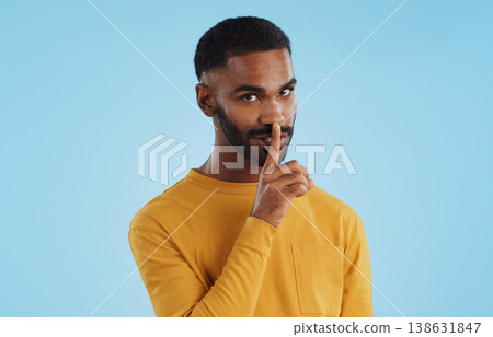 Secret, face and man with finger on lips in studio for quiet, privacy or hush news on blue background. Whisper, drama and portrait of guy model with confidential hand emoji for gossip or announcement Secret, face and man with finger on lips in studio for quiet, privacy or hush news on blue background. Whisper, drama and portrait of guy model with confidential hand emoji for gossip or announcement 138631847