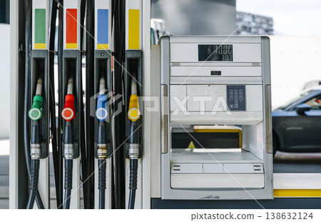 Fuel pump nozzles hanging at a modern gas station during a period of high oil prices. A conceptual photography showcasing the global energy crisis, increasing gasoline costs 138632124