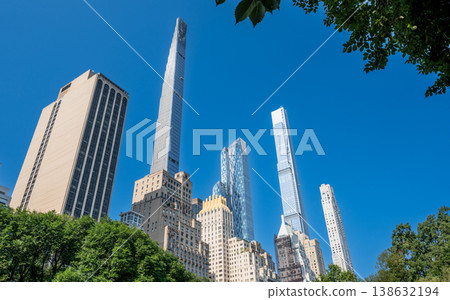 New york, usa august 14,2024. Tall, modern skyscraper buildings dominate manhattan skyline, rising behind green tree canopy of central park on a clear day New york, usa august 14,2024. Tall, modern skyscraper buildings dominate manhattan skyline, rising behind green tree canopy of central park on a clear day 138632194