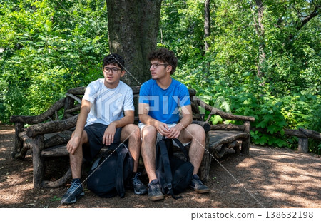 New york, usa august 14,2024. Two friends sitting on a wooden bench in a sunny central park, relaxing among green trees during a summer day in manhattan 138632198