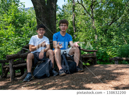 New york, usa august 14,2024. Two friends sitting on a rustic bench, enjoying their time together in the natural setting of central park, manhattan, new york New york, usa august 14,2024. Two friends sitting on a rustic bench, enjoying their time together in the natural setting of central park, manhattan, new york 138632200