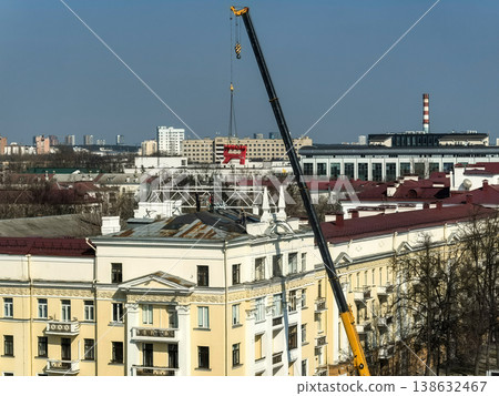 Crane installing large red letter sign on historic building roof in city center Crane installing large red letter sign on historic building roof in city center 138632467