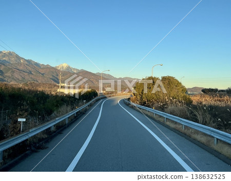 傍晚時分,一條公路蜿蜒通往山脈,遠處是鄉村景觀(日本,無人居住)。 傍晚時分,一條公路蜿蜒通往山脈,遠處是鄉村景觀(日本,無人居住)。 138632525