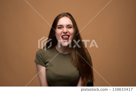 Young woman making a playful grimace while sticking out tongue, expressing a humorous and goofy mood Young woman making a playful grimace while sticking out tongue, expressing a humorous and goofy mood 138633417