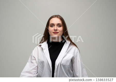 Young woman posing, wearing a white shirt and black top. Studio portrait of a female with long brown hair Young woman posing, wearing a white shirt and black top. Studio portrait of a female with long brown hair 138633527