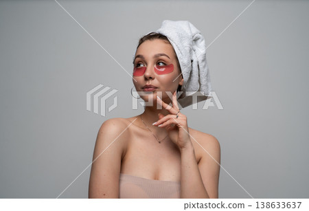Young woman enjoying self-care routine with under-eye patches and head towel, feeling relaxed and pampered, taking time for wellness and beauty skincare treatment Young woman enjoying self-care routine with under-eye patches and head towel, feeling relaxed and pampered, taking time for wellness and beauty skincare treatment 138633637