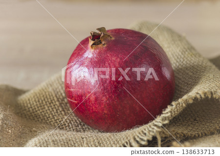 A Pomegranate or grenade on a burlap background, close up A Pomegranate or grenade on a burlap background, close up 138633713