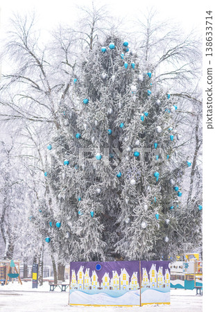 Decorated christmas tree with snow in a winter square Decorated christmas tree with snow in a winter square 138633714