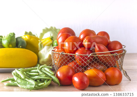 Various fresh vegetables: tomatoes, green beans, cucumbers, cabbage on a woodent table agaisnt white background; copy space Various fresh vegetables: tomatoes, green beans, cucumbers, cabbage on a woodent table agaisnt white background; copy space 138633715