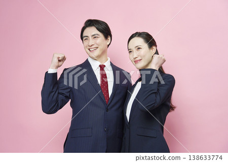 一位商人和一位女商人以粉紅色背景擺出勝利姿勢。 138633774