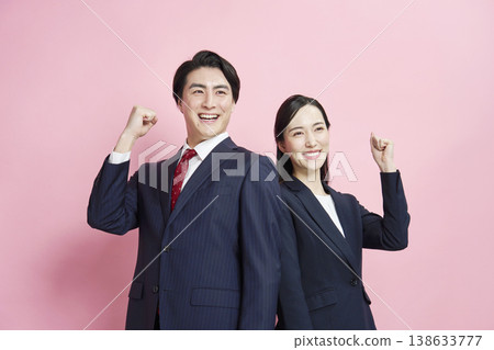 一位商人和一位女商人以粉紅色背景擺出勝利姿勢。 138633777