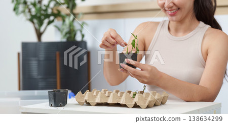 Woman planting seedlings in eco-friendly pots indoors Woman planting seedlings in eco-friendly pots indoors 138634299
