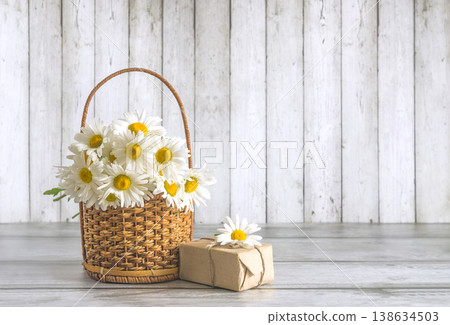 Happy birthday or mothers day concept; bouquet of white daisy flowers, craft gift box on a wooden table; copy space Happy birthday or mothers day concept; bouquet of white daisy flowers, craft gift box on a wooden table; copy space 138634503