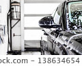 Car wash, black car covered foam at indoor station. Side view with mirror and body panels in soap, cleaning process, glossy surface care, automotive washing and detailing service 138634654