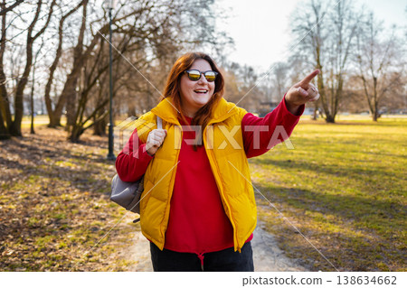 Close up of cheerful young girl pointing away while standing at the park Close up of cheerful young girl pointing away while standing at the park 138634662