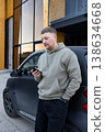 Man using smartphone standing near car outdoors 138634668