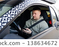 Driver using smartphone while wearing seatbelt in parked car 138634672