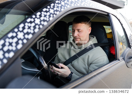 Driver using smartphone while wearing seatbelt in parked car 138634672