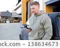 Man using smartphone standing near car outdoors 138634673